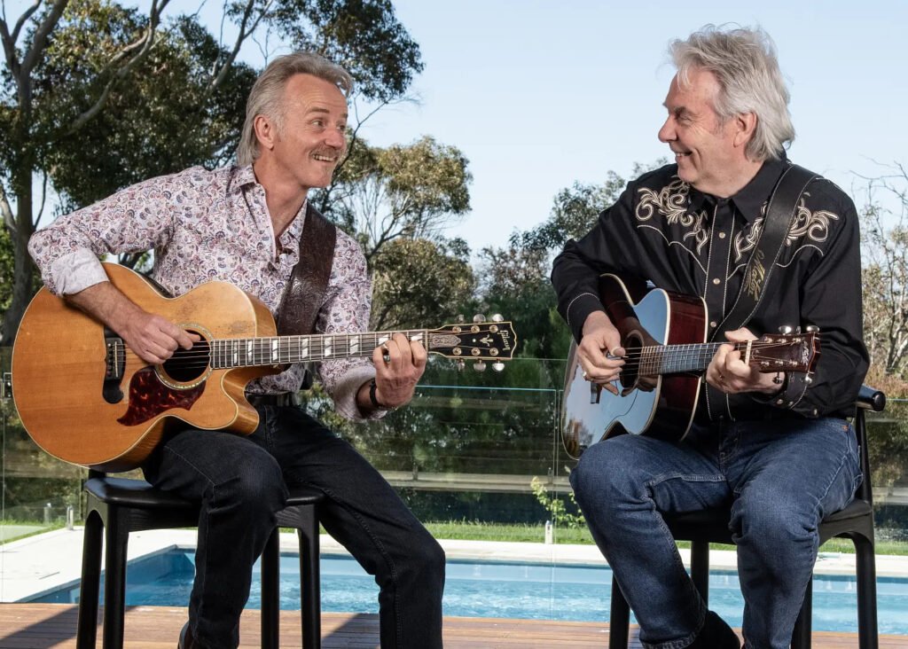 Geoff Achison and Nick Charles playing acoustic guitars together.
